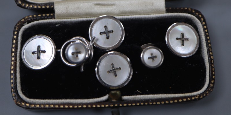 A white metal (stamped 9ct) and mother of pearl set six piece dress stud set, gross weight 6.3 grams.